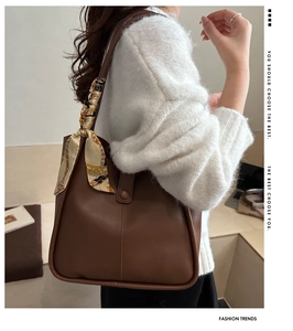 Detail of a brown matte leather shoulder bag featuring a stylish floral silk scarf detail