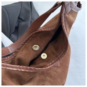 Detail shot of the golden magnetic closure and suede texture of this brown shoulder bag