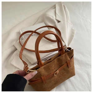 Detailed close-up of a caramel suede tote bag with leather strap and metal buckle detail
