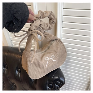 Détail du sac croissant en velours côtelé kaki avec poignée plissée et nœud blanc
