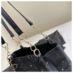 Detail of black tote bag with silver star moon print and gold metal chain strap