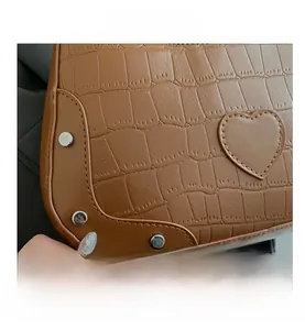 Detail of brown crocodile pattern handbag featuring a heart patch and silver metal rivets
