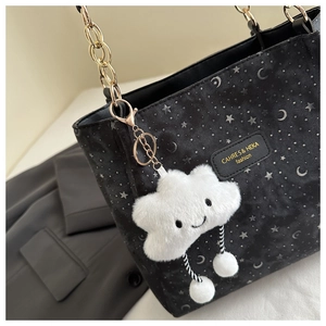 Detail of black tote bag featuring gold chain, star moon print, and white cloud charm