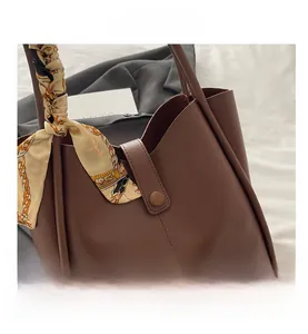 Detail view of large brown tote bag with thick side stitching and a decorative silk scarf