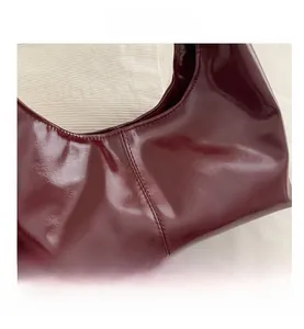 Detail of dark red glossy patent leather tote with professional double stitching lines