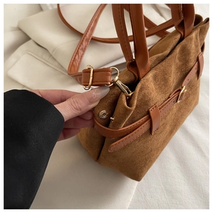 Detailed close-up of brown frosted leather bucket bag showing golden metal buckle and texture
