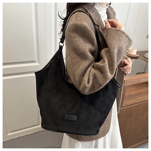 Close-up of a black matte tote bag showing the fine suede texture and leather shoulder strap