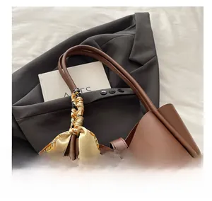 Detail of a brown leather tote bag with decorative silk scarf on a grey suit jacket