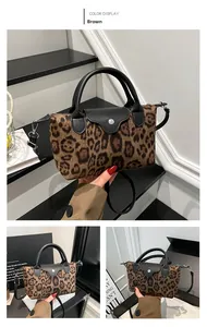 Detail view of leopard print canvas shoulder bag with black leather handle and strap