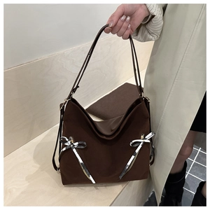 Close-up of dark brown tote bag with decorative black and white striped bows and gold zippers