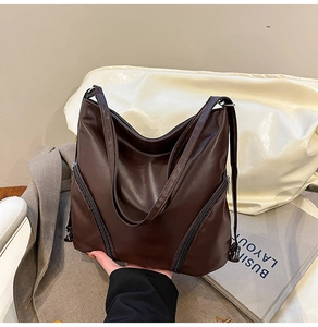 Détail d'un grand sac cabas en similicuir marron avec bandoulière large et zips décoratifs