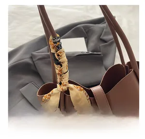 Close-up of elegant horsebit print silk scarf tied as a decorative bag accessory