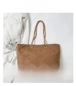 Detail of coffee brown quilted bucket bag with gold chain strap and suede texture