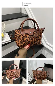 Close-up of yellow leopard rose print handbag with brown leather handle and flap
