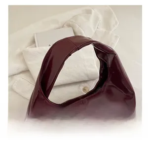 Detail showing the comfortable handle and glossy patent leather finish of the burgundy tote bag