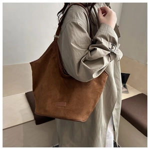 Caramel brown suede tote bag detail with minimalist leather label and shoulder strap