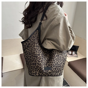 Detailed view of canvas tote bag featuring classic leopard print and black strap details
