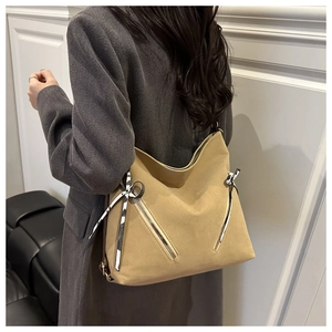 Detail of khaki tote bag with double zippers and striped ribbon on model's shoulder