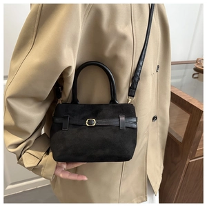 Close-up of black suede tote bag featuring fine texture and golden metal buckle details