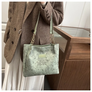 Close-up of light green suede tote bag with star and moon embossing and chain strap