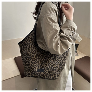 Detail of large leopard print hobo bag with black straps on shoulder of model