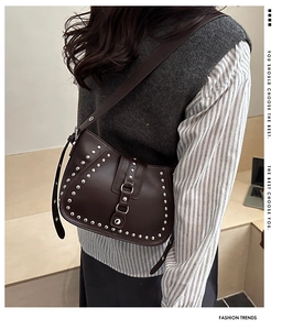 Close-up of retro dark brown leather crossbody bag with silver studs and adjustable strap
