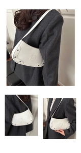 Detail of white crocodile embossed underarm bag with heart stitching and metallic rivets