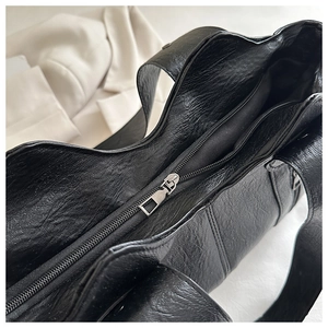 Close-up of black wrinkled leather tote bag showing smooth zipper closure and texture
