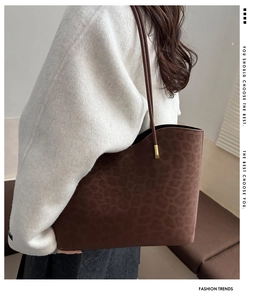 Detail of leopard print tote bag featuring matte texture and gold hardware accents