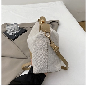 Detail of cream canvas bucket bag with camel leather trim and gold metal buckles