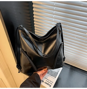 Détail d'un grand cabas en similicuir noir montrant la texture lisse et les deux fermetures