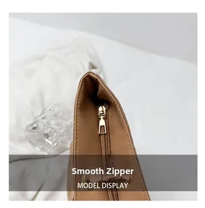 Detail of smooth gold metal zipper and stitching on a brown leather tote bag