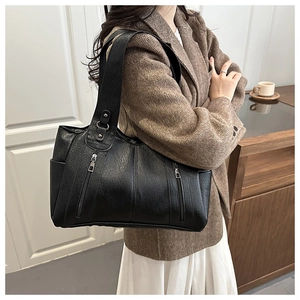 Detailed view of black faux leather tote with dual vertical zippers and large capacity