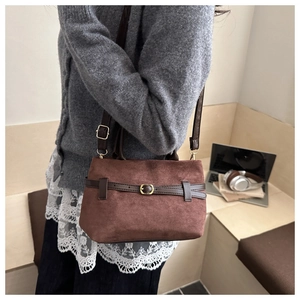 Close-up of vintage brown suede tote bag with leather strap and golden buckle detail
