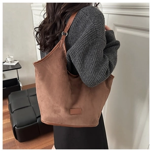 Brown suede shoulder bag styled on model with grey knit sweater and urban decor
