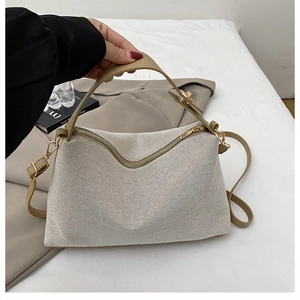 Detail of woven Boston bag with cream mesh, brown leather handles and gold hardware