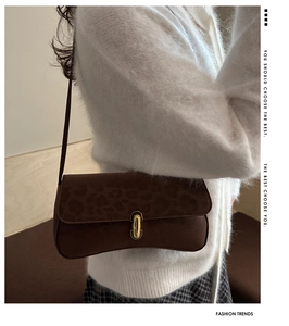 Detail of a brown leopard print shoulder bag with a gold oval metal lock and suede texture