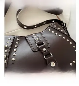 Close-up of vintage dark brown faux leather bag with silver rivets and buckle closure