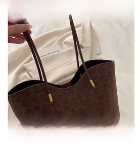 Close-up of leopard print tote bag featuring brown handles and gold hardware accents