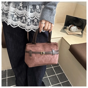 Gros plan sur un sac seau en daim marron avec sangles décoratives et boucle dorée