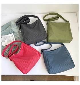 Vue à plat de sacs bandoulière en toile à carreaux noirs, verts, rouges et bleu marine