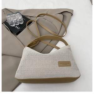 Detail of cream fabric and brown leather patchwork shoulder bag with brand logo tag