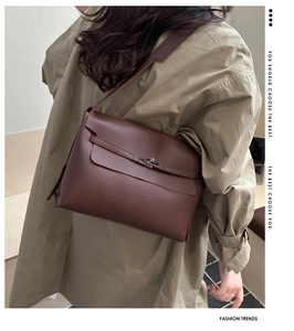 Detail of dark brown leather shoulder bag with silver clasp and adjustable strap