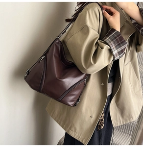 Détail du sac à épaule en cuir marron foncé avec fermeture éclair latérale élégante