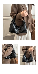 Detail view of glossy black hobo shoulder bag with mirror finish and curved handle
