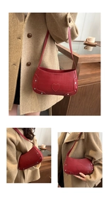 Close-up of red crocodile pattern bag with silver studs and heart patch detail