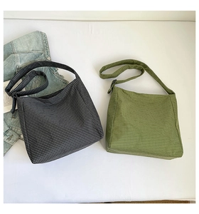 Détail de sacs à bandoulière en toile à carreaux gris et verts avec sangle réglable