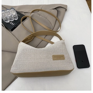 Detail of woven cream fabric texture with brown leather strap on a chic shoulder bag