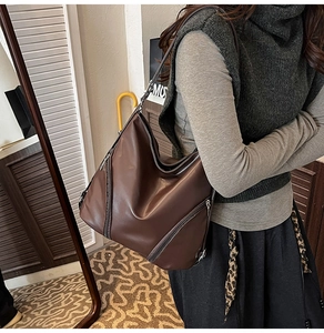 Vue détaillée du sac bandoulière en cuir marron foncé avec fermeture éclair décorative