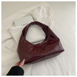 Detail view of burgundy hobo bag in glossy patent leather on white background